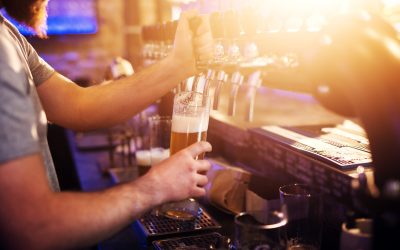 Close up focus view of waiter pouring draft beer in the sunny bar.